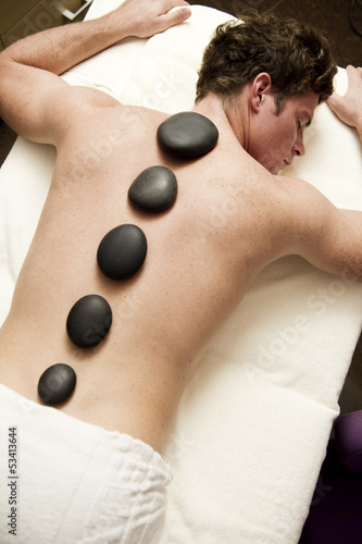 Photo: Young man doing hot stone therapy Young man doing hot stone therapy