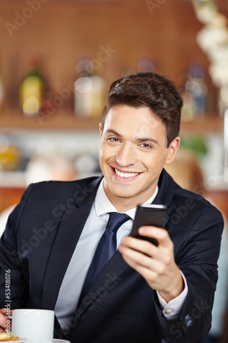 Photo: Geschäftsmann sitzt im Café mit Smartphone Geschäftsmann sitzt im Café mit Smartphone