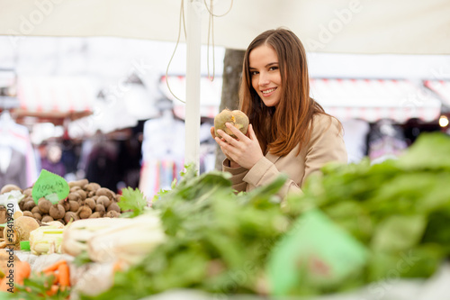 Photo: Young woman buying vegetables at farmer's market Young woman buying vegetables at farmer's market