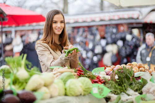 Photo: Young woman showing farmer which peppers she'd like to buy. At t Young woman showing farmer which peppers she'd like to buy. At t
