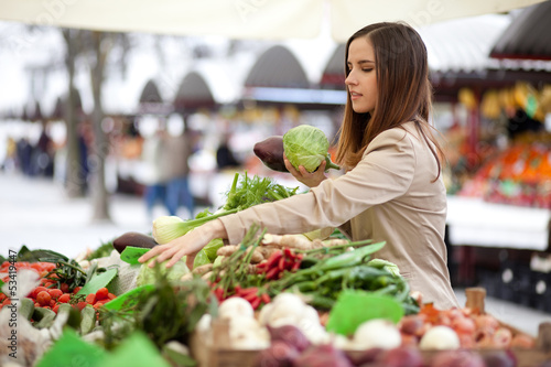 Photo: Young woman picking vegetables at farmer's market Young woman picking vegetables at farmer's market