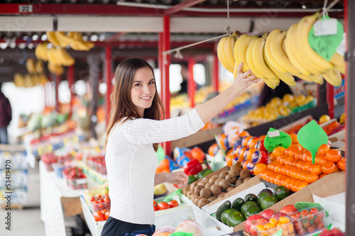Photo: Young woman buying bananas at the market Young woman buying bananas at the market