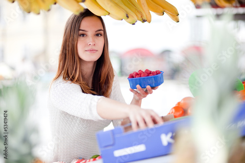 Photo: Young woman reaching for fruit at the farmer's market Young woman reaching for fruit at the farmer's market