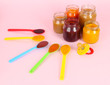 Baby puree in spoons with nipple on pink background