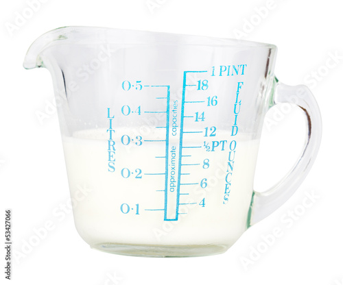 Photo: Measuring cup containing milk isolated on white Measuring cup containing milk isolated on white