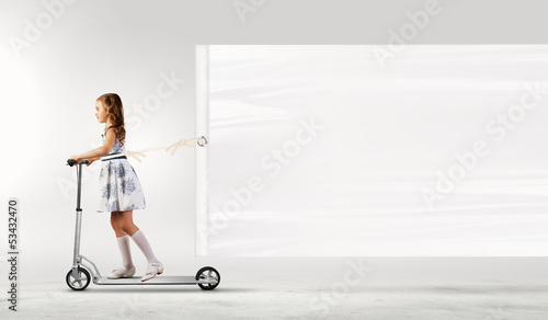 Photo: Little girl riding scooter Little girl riding scooter