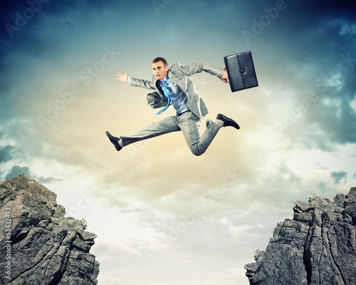 Photo: Businessman jumping over gap Businessman jumping over gap