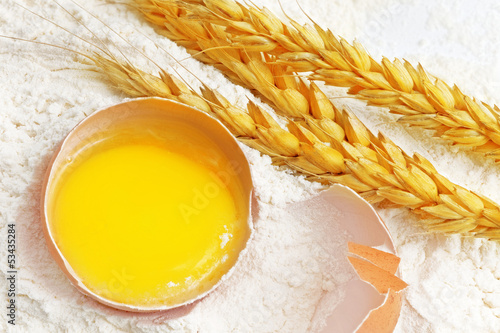 Photo: Spikelets of wheat on flour spillage.Isolated. Spikelets of wheat on flour spillage.Isolated.