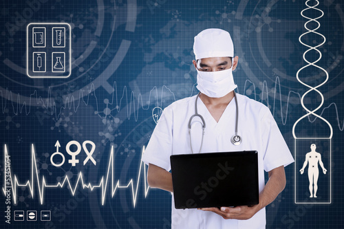 Photo: Doctor hold laptop on blue digital background Doctor hold laptop on blue digital background