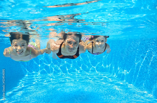 Photo: Happy family swim underwater in pool, having fun on vacation Happy family swim underwater in pool, having fun on vacation