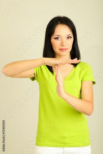 Photo: Girl showing time out sign on grey background Girl showing time out sign on grey background