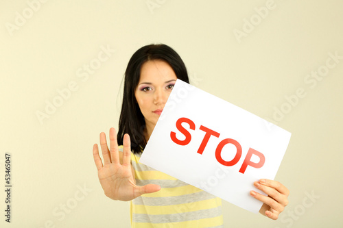 Photo: Girl showing stop sign on grey background Girl showing stop sign on grey background