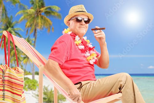 Photo: Gentleman smoking a cigar and enjoying on a sun lounger on a bea Gentleman smoking a cigar and enjoying on a sun lounger on a bea