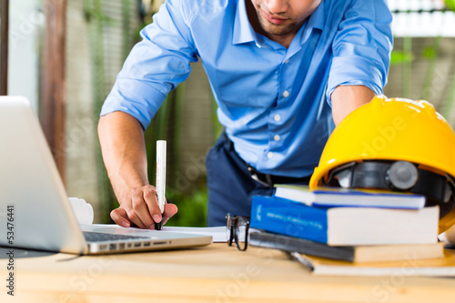 Photo: Architect working at home on a design or draft Architect working at home on a design or draft