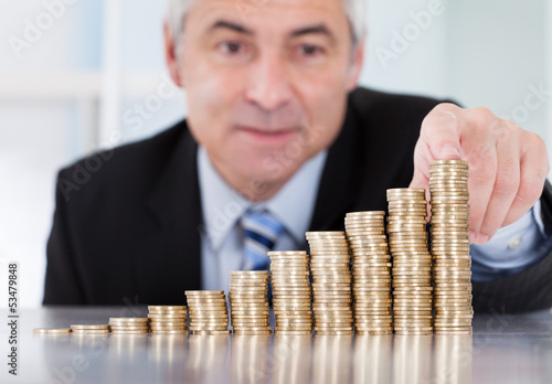 Photo: Mature Businessman With Stack Of Coins Mature Businessman With Stack Of Coins