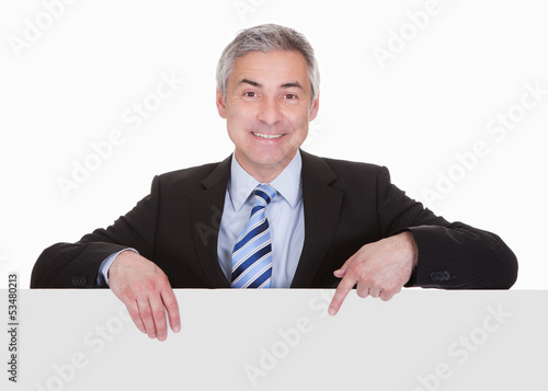 Photo: Mature Businessman Pointing At Placard Mature Businessman Pointing At Placard