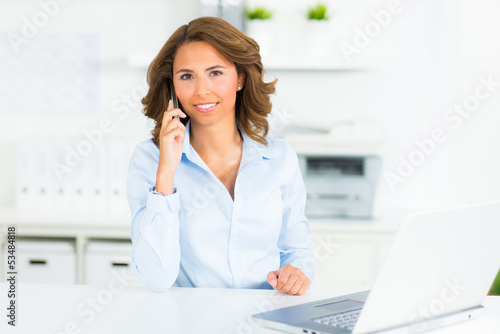 Photo: businesswoman with her cell phone in the office businesswoman with her cell phone in the office