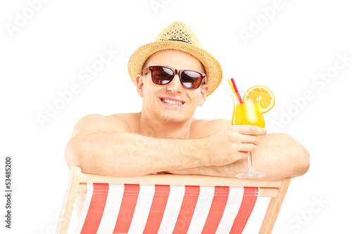 Photo: Smiling shirtless guy with cocktail posing on a beach chair Smiling shirtless guy with cocktail posing on a beach chair