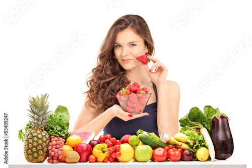 Photo: Young female holding a bowl of strawberries and posing behind a Young female holding a bowl of strawberries and posing behind a