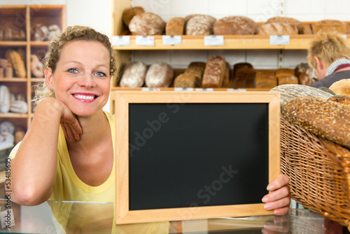 Photo: salesclerk holding a billboard in a bakery salesclerk holding a billboard in a bakery
