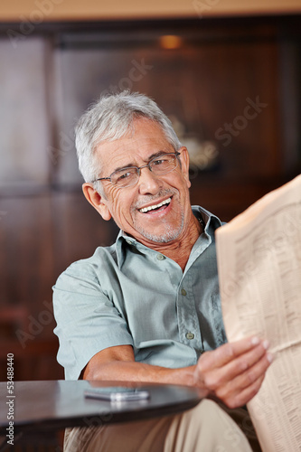 Photo: Senior man with glasses reading newspaper Senior man with glasses reading newspaper