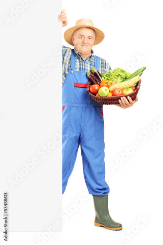 Photo: Mature gardener holding a basket full of fruits and vegetables Mature gardener holding a basket full of fruits and vegetables
