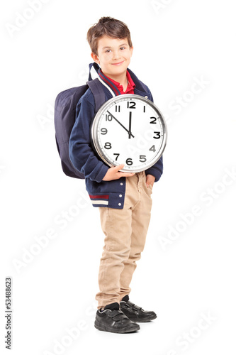 Photo: Full length portrait of a school boy with backpack holding a clo Full length portrait of a school boy with backpack holding a clo