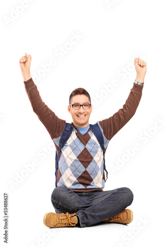 Photo: Handsome young man sitting on a floor with raised hands gesturin Handsome young man sitting on a floor with raised hands gesturin