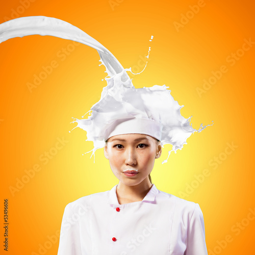 Photo: Asian female cook against milk splashes Asian female cook against milk splashes