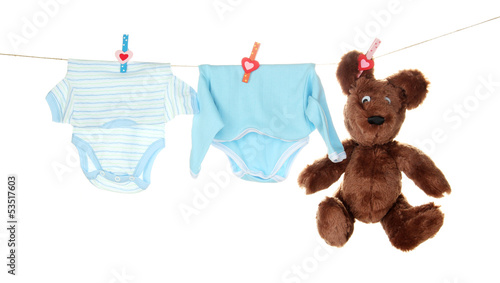 Photo: Baby clothes hanging on clothesline, isolated on white Baby clothes hanging on clothesline, isolated on white