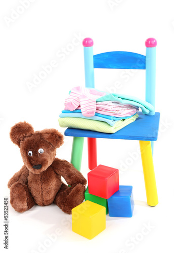Photo: Small and colorful chair with baby clothes isolated on white Small and colorful chair with baby clothes isolated on white