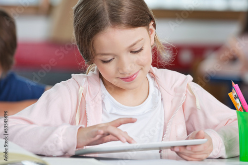 Photo: Schoolgirl Smiling While Using Tablet At Desk Schoolgirl Smiling While Using Tablet At Desk