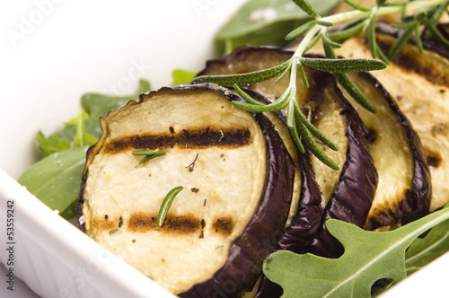 Photo: Grilled eggplant slices on a plate with fresh rosemary Grilled eggplant slices on a plate with fresh rosemary