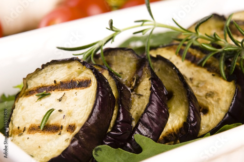Photo: Grilled eggplant slices on a plate with fresh rosemary Grilled eggplant slices on a plate with fresh rosemary