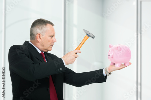 Photo: Man breaking a piggy bank Man breaking a piggy bank