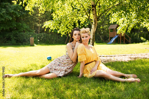 Photo: Two attractive women resting on the flower meadow Two attractive women resting on the flower meadow