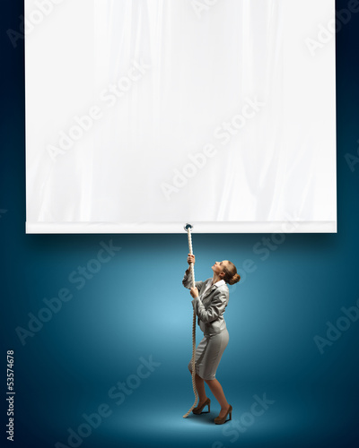 Photo: Businesswoman pulling blank banner Businesswoman pulling blank banner
