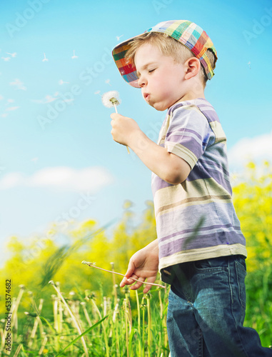 Photo: Young cheerful boy playing blow-ball Young cheerful boy playing blow-ball