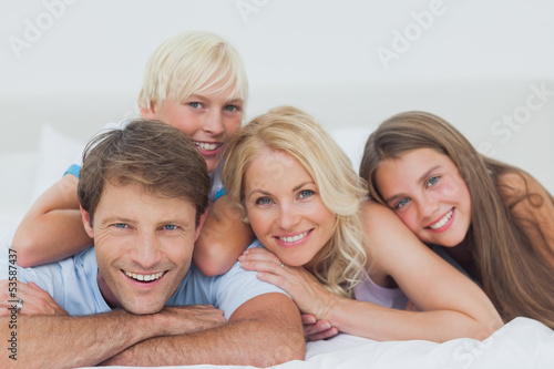 Photo: Smiling family lying on bed Smiling family lying on bed