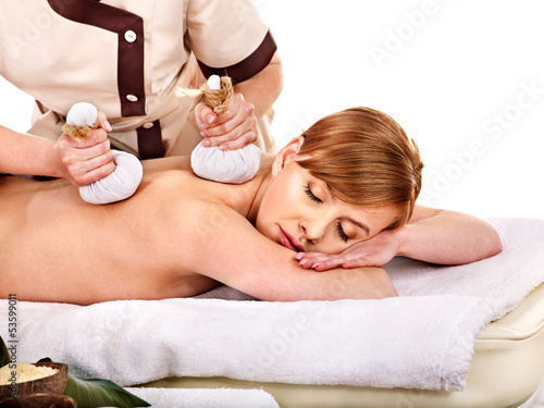 Photo: Woman getting herbal ball massage treatments . Woman getting herbal ball massage treatments .