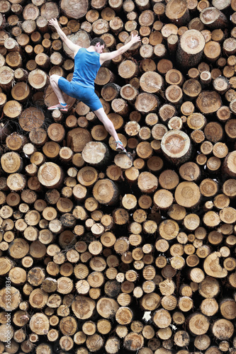 Photo: Fit climber going down the large pile of cut wooden logs Fit climber going down the large pile of cut wooden logs