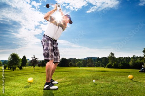 Photo: Young golf player on course doing golf swing Young golf player on course doing golf swing