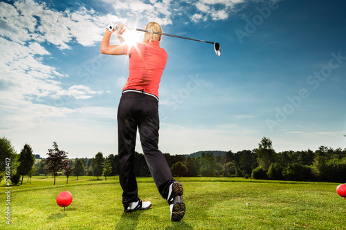 Photo: Young golf player on course doing golf swing Young golf player on course doing golf swing