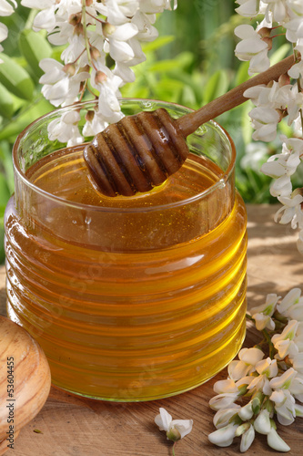 Photo: Acacia honey jar with a dipper and Acacia tree blossoms Acacia honey jar with a dipper and Acacia tree blossoms