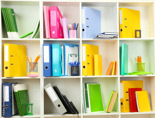 Photo: White office shelves with different stationery, close up White office shelves with different stationery, close up