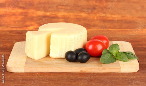 Photo: Cheese mozzarella,basil and vegetables on wooden background Cheese mozzarella,basil and vegetables on wooden background