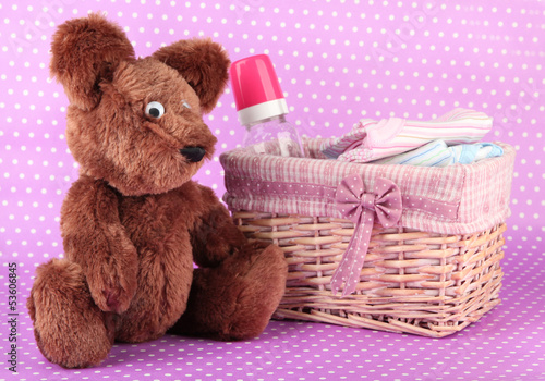 Photo: Beautiful basket of baby clothes on a pink background Beautiful basket of baby clothes on a pink background