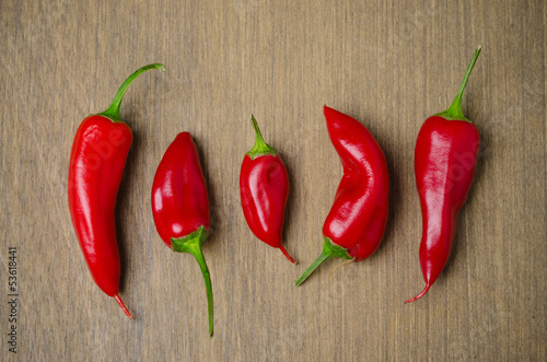 Photo: red hot chili peppers on a brown wooden background red hot chili peppers on a brown wooden background