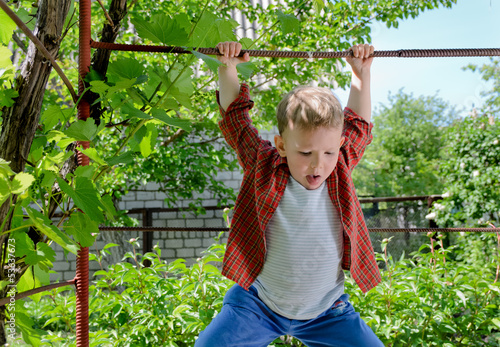 Photo: Happy young boy swinging on a metal bar Happy young boy swinging on a metal bar