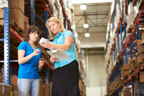 Photo: Businesswoman And Female Worker In Distribution Warehouse Businesswoman And Female Worker In Distribution Warehouse